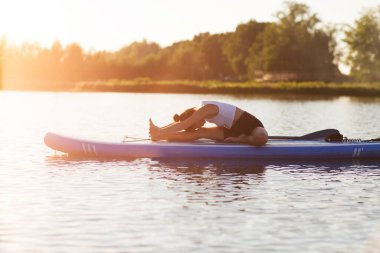 Gün batımında yemek güvertesinde yoga yapan bir kadın. Açık hava yaz aktivitesi. N 'aber yoga. Sosyal Mesafe. Boşluğu kopyala