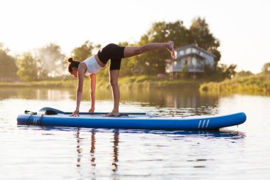 Gün batımında yemek güvertesinde yoga yapan bir kadın. Açık hava yaz aktivitesi. N 'aber yoga. Sosyal Mesafe. kopyalama alanı. Akıl Sağlığı