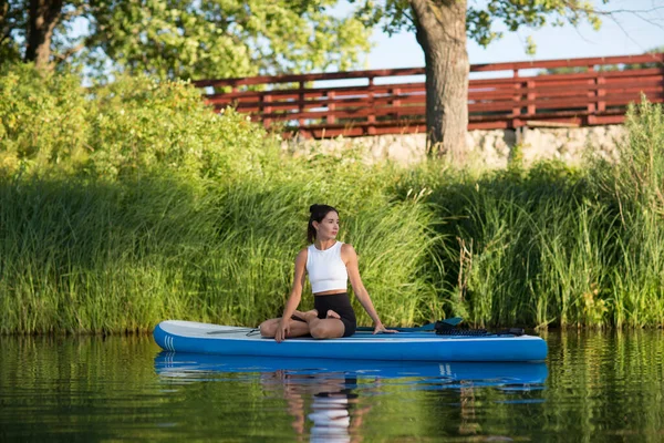woman doing yoga on sup board at sunset. outdoor summer activity. Sup yoga. Social Distancing. copy space