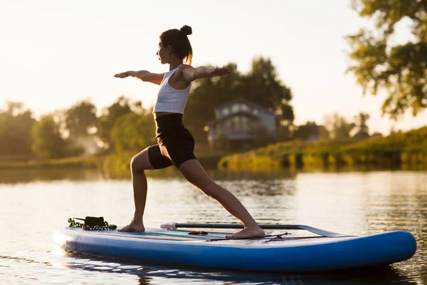 woman doing yoga on sup board at sunset. outdoor summer activity. Sup yoga.  Social Distancing. copy space. Mental Health