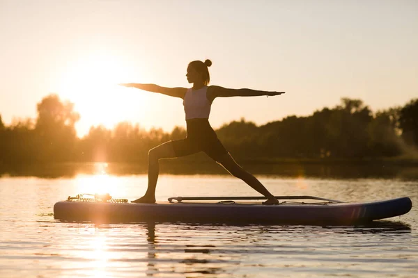 Gün batımında yemek güvertesinde yoga yapan bir kadın. Açık hava yaz aktivitesi. N 'aber yoga. Sosyal Mesafe. kopyalama alanı. Akıl Sağlığı