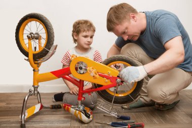 Baba ve oğlu evdeki bisikleti tamir ediyorlar.