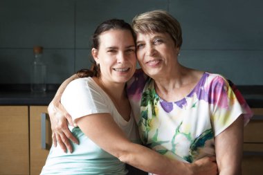 Sevimli genç bir kadın ve annesinin mutfakta kucaklaşması. çok nesilli aile