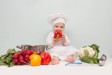Sebzeli ve tavalı bir şef şapkası takan bebek..
