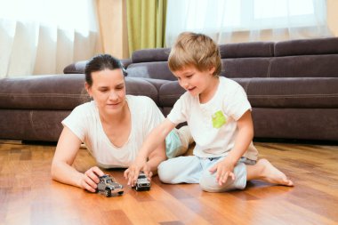 Anne ve küçük oğlu oturma odalarında araba oyuncakları oynuyorlar. Mutlu aile evde birlikte vakit geçirir..