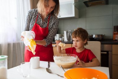 Anne ve küçük oğlu hamuru pişiriyor, evde mutfakta kurabiye pişiriyor. Gerçek hayatta sıradan bir fotoğraf serisi.  