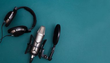 Arka fonda kulaklık ve dalga boyu olan profesyonel mikrofon. Podcast veya kayıt stüdyosu arka planı