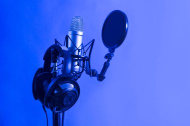 Professional microphone with waveform and headphones a on blue background banner. Podcast or recording studio background clipart