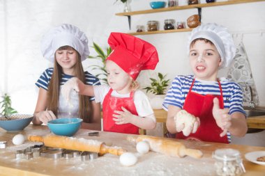 Küçük mutlu çocuklar aşçılar mutfakta kurabiye hazırlıyorlar..