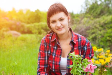 Young woman gardening and holding flowers  in summer.  Spring Awakening. cottagecore. slow life. pastoral life.  enjoy the little things. 