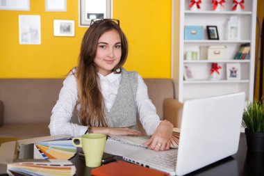  attractive young woman  designer  working with laptop in the home, drinking coffee. home office.