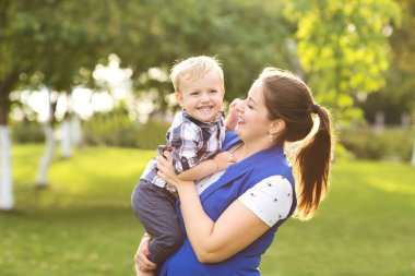 Anne ve küçük oğlu yazın açık havada sarılıp oynuyorlar..