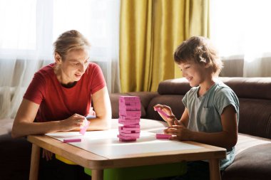 Anne ve oğlu evde masa oyunu oynarken eğleniyorlar. 
