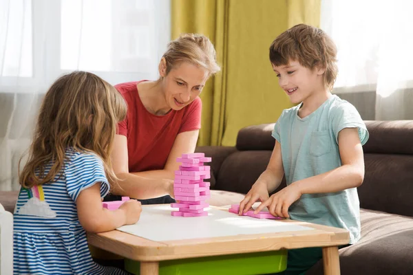 Mom and two kids playing  board game together at home.  Family having fun playing at home. Family board games.