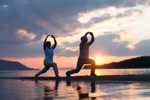 Erkek ve kadın sahilde gün batımında Tai Chi chuan yapıyorlar. tek başına açık hava aktiviteleri. Sosyal Mesafe. Sağlıklı yaşam tarzı kavramı. 