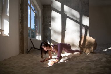 Genç bir kadın, kumda, ağaçların gölgelerinde fotokopi alanı olan bir yoga egzersizi yapıyor. Aktif giysi. Sağlıklı ve spor yaşam tarzı.