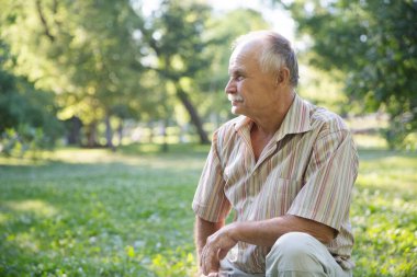 Son sınıf öğrencisi parkta çimlerin üzerinde oturuyor.