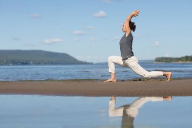 Plajda tai chi chuan yapan bir kadın. Çin yönetimi yeteneği Qi 'nin enerjisi. tek başına açık hava aktiviteleri. Sosyal Mesafe 