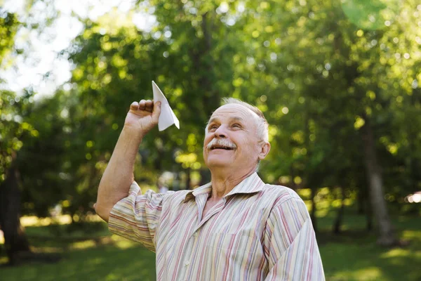 老人は公園で紙飛行機を操縦する 夏休み — ストック写真