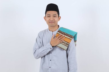 Geleneksel giysili, beyaz halısı olan mutlu Endonezyalı genç adam. Samimi Bayram Mübareği veya Ramazan Kareem karşılama kavramı.