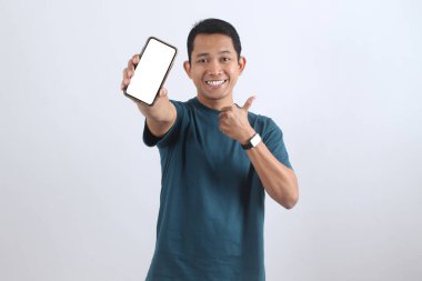 Gülümseyen adam bir ürün öneriyor, uygulamanız veya web siteniz için beyaz ekranlı bir akıllı telefon tutuyor ve onay için onay veriyor.