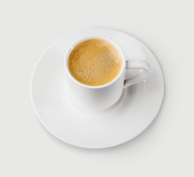 Bir fincan köpüklü küçük bir fincan kahve, bir fincan beyaz çay tabağında, yakın plan...