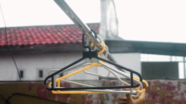 Dinamik bir videoda elbise askıları kırmızı çatılı bir evin arka planında sallanıyor, evcillik ve günlük yaşam duygusunu yakalıyor..