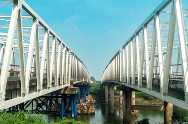 Endonezya 'nın Doğu Java kentindeki Brantas Nehri boyunca uzanan ikiz çelik köprüler, parlak bir gökyüzü altında katı sütunlar tarafından desteklenmektedir. Seyahat, ulaşım ve altyapı temaları için ideal modern bir dönüm noktası