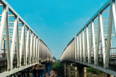 Doğu Java, Endonezya 'da sağlam beton sütunlarla desteklenen Brantas Nehri boyunca uzanan iki çelik köprü. Modern altyapı seyahat, inşaat ve kentsel kalkınma teması için ideal