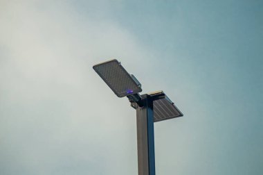 Soluk gökyüzüne karşı bir güneş ışığı, kentsel aydınlatma ve altyapı gelişimi için sürdürülebilir enerji çözümlerini gösteren, yeşil teknoloji ve çevre dostu tasarımları destekleyen.