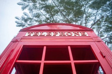 Üzerinde telefon sözcüğü olan kırmızı bir İngiliz telefon kulübesinin kapağı. Ağaç dalları üzerine kurulmuş. Nostalji ve İngiliz kültürünü çağrıştırıyor..