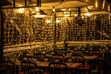 Geceleri Masalar ve Sıcak İp Işıklarıyla Samimi Açık Yemek Alanı