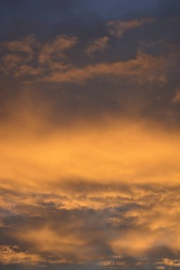 Koyu turuncu bulutlar ve zengin doku ile karanlık, kasvetli günbatımı gökyüzü dramatik atmosferik derinlik yaratıyor..