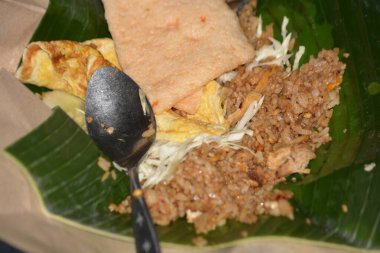 Lezzetli Nasi Goreng omlet dilimleri, krakerler ve lahana, muz yaprağı üzerinde sunuluyor, klasik Endonezya konfor yemeği, yakın çekim