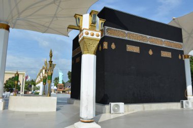 15 Haziran 2025 'te Madiun Endonezya' da İslami temalı bir meydanda sütunlar ve şemsiyelerle çerçevelenmiş bir Kabe kopyası için daha yakın duvar görüntüsü