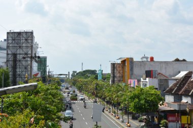 15 Haziran 2025 'te Madiun Endonezya' da şehir koridoru manzarası. Gün ortasında hareket halindeki ağaçlar ve haber ve editoryal habercilik için yukarıdan yakalanan karışık mimari çizgileri ile birlikte.