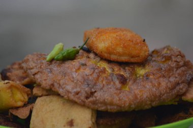 Kızarmış sokak atıştırmalıkları açık havada çekilmiş yeşil bir tabakta sokak yemekleri ve abur cubur temaları için uygun yumuşak arka plan bulanıklığı ile