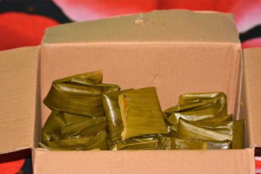 Katlanmış muz yaprağı paketleri ile dolu açık bir karton kutunun en üstteki görüntüsü paket servis siparişi ya da toplumsal etkinlikler için uygun geleneksel Endonezya atıştırmalıkları