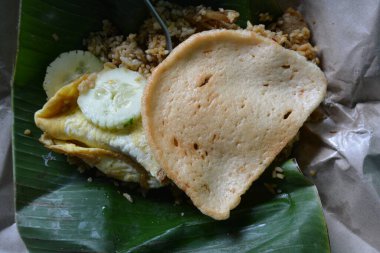 Nasi goreng porsiyonu omlet ve muz yaprağına yerleştirilmiş doğranmış lahana geleneksel paket paket Endonezya 'dan izleniyor.