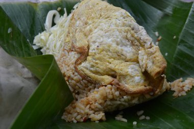 Muz yapraklı Nasi Goreng porsiyonu. Yumurta omleti ve çiğ lahana. Geleneksel kağıt ambalajla paketlenmeye hazır.