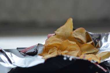 Kıtır kenarları ve parlak folyo üzerindeki altın cips dokusunu gösteren dar makro tasarım geçmişi ve yemek reklamları için ideal bir açık büfe.