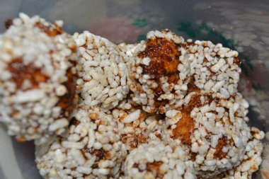 Bir el, şişirilmiş pirinç topuna uzanıyor. Benzer ikramlarla dolu bir konteynerin üzerinde. Tercih edilen temalar için kullanışlı porsiyon kontrolü ve günlük yemek anları.