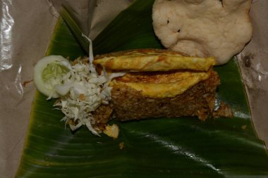 Muz yaprağında servis edilen Nasi Goreng 'in üst açısı lahana salatalığı ve krakerle servis ediliyor..