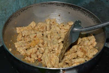 Tempeh parçaları Endonezya yemeği hazırlarken metal bir tavada hafif kahverengiye kadar pişirilir..