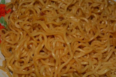 Yemek arkaplanı çizimleri ve mutfak içeriği için ideal dokuyu ve rengi gösteren pişmiş eriştenin detaylı yakın plan fotoğrafı.