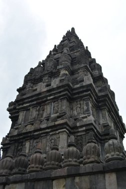 Yogyakarta Endonezya 'da 21 Şubat 2026' da oyulmuş kabartmaları, köşeleri ve koyu taş dokusunu vurgulayan bir Prambanan yan tapınağının düşük açılı görüntüsü