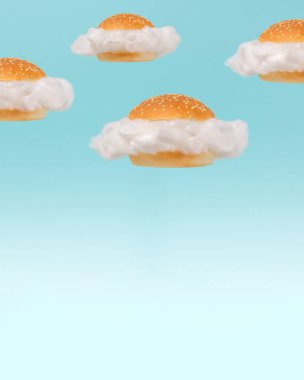 Hamburgerin içindeki beyaz bulutlar mavi gökyüzü arka planında yüzüyor. Sürreal fast food grubu konsepti. Asgari soyut yaz sağlıklı beslenme fikri.