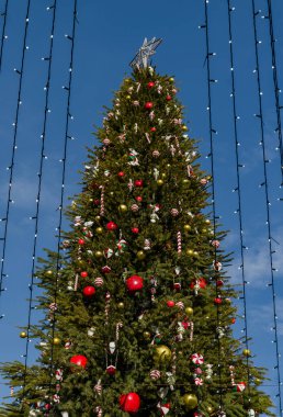 Mavi gökyüzünün arka planında süslemeleri olan Noel ağacı, kapat