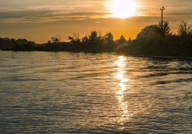 Günbatımı güneşi suda yansıyor, güzel bir sonbahar akşamı manzarası.