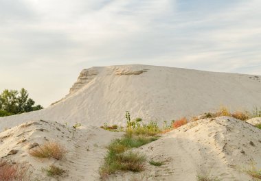 Bir yaz günü, bulutlu bir gökyüzünün arka planında nehir kumu olan bir dağ.
